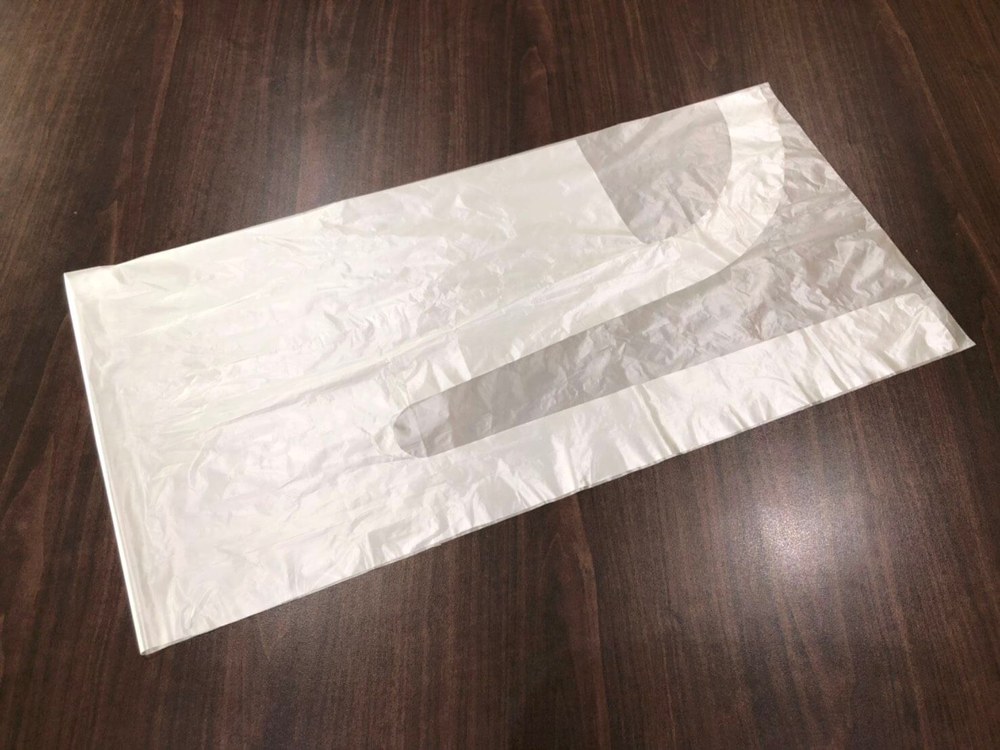 Disposable PE apron blank cut from film, showing the neck opening before unfolding